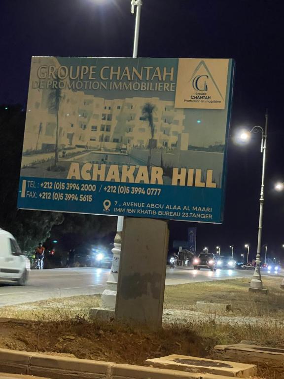 a sign in front of a building at night at Casa étoile, Appartement avec piscines, vue sur mer et accès à la plage à Achakar Hill, Tanger in Tangier
