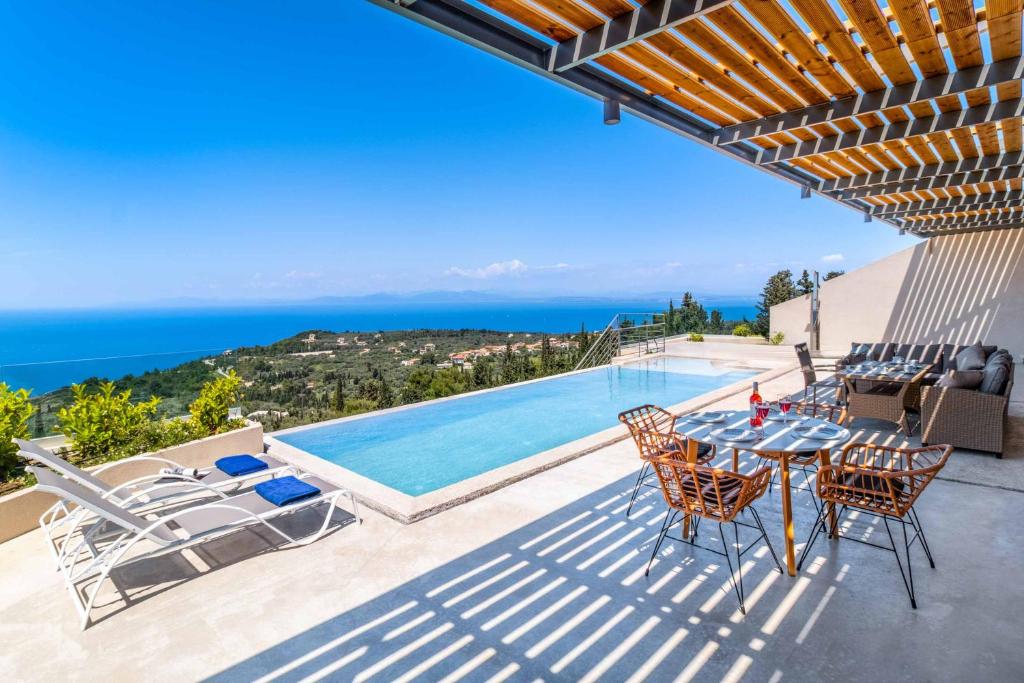 a patio with a table and chairs next to a swimming pool at Villa Andromeda Sunset in Tsoukalades