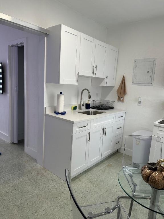 a kitchen with white cabinets and a sink and a table at Villa Clara ICON-Little Havana in Miami