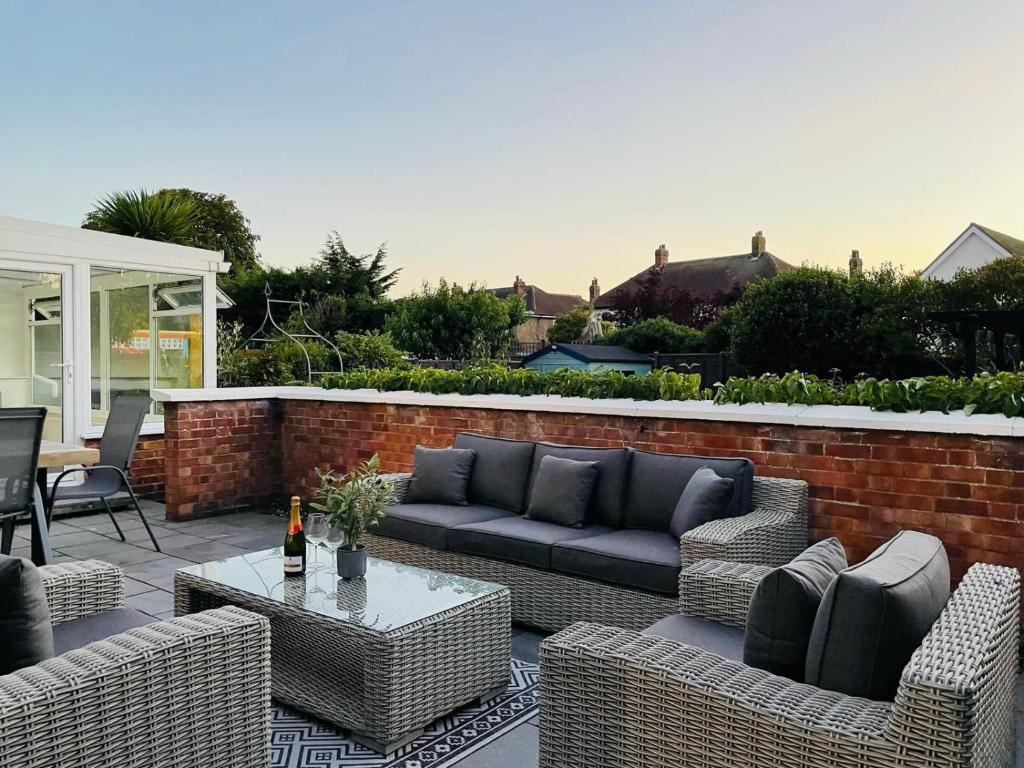a patio with wicker furniture and a brick wall at Large villa opposite beach in Great Yarnouth in Great Yarmouth