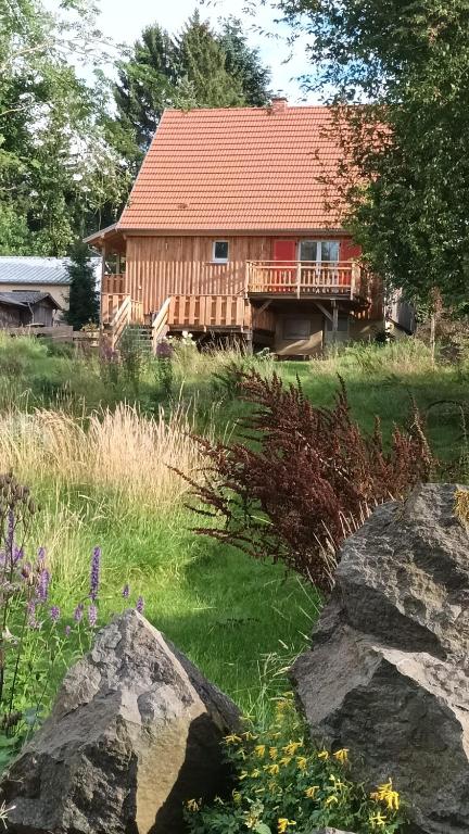 a log cabin with a red roof and some rocks at Ferienhaus Hoher Vogelsberg in Herbstein