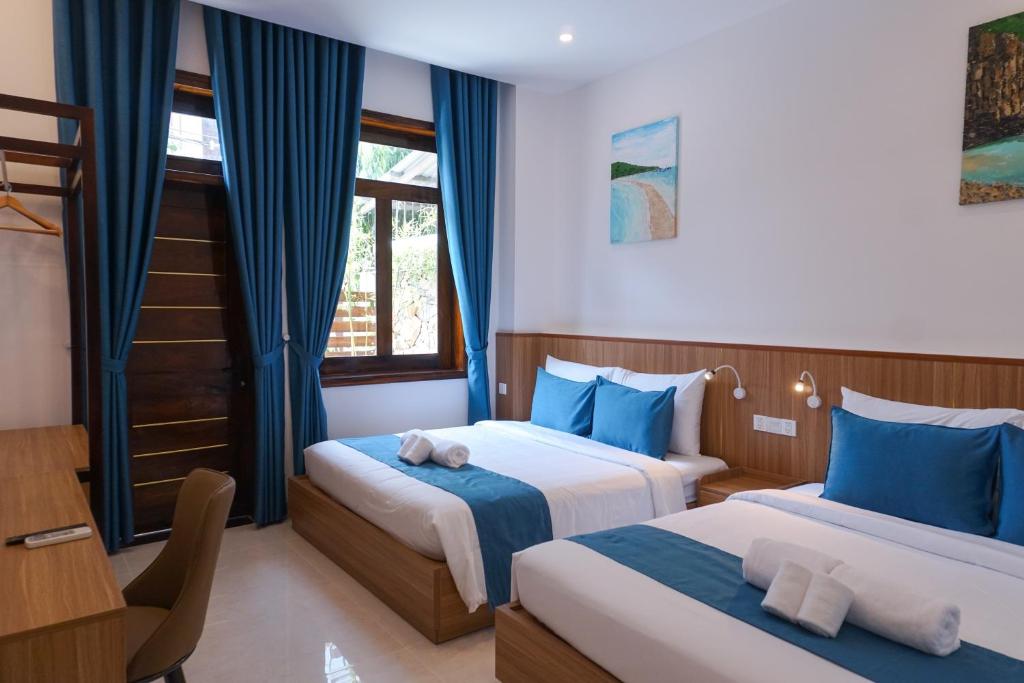 ein Hotelzimmer mit zwei Betten und einem Schreibtisch in der Unterkunft CLOVER Homestay Phú Yên in Phường Sáu