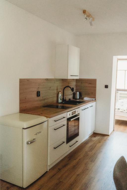 a kitchen with white cabinets and a sink at Apartmány Borovice in Josefŭv Dŭl