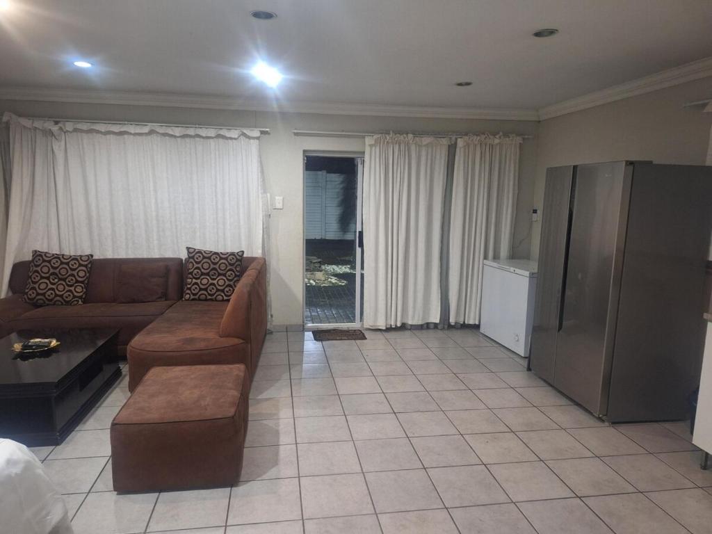 a living room with a couch and a tv at Bella Cottage Escape in Rooihuiskraal