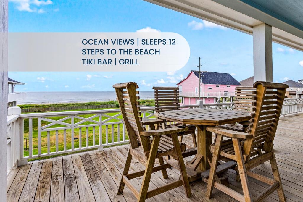 a wooden table and chairs on a deck with the beach at Salty Seabass 4BR Seaside Escape in Port Bolivar