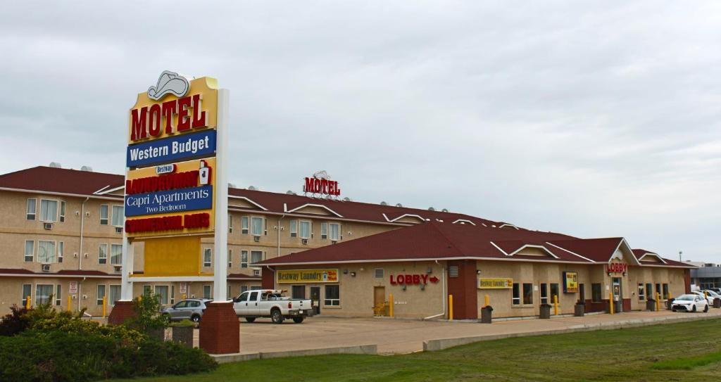 a motel with a sign in front of a building at Western Budget Motel Ponoka in Ponoka