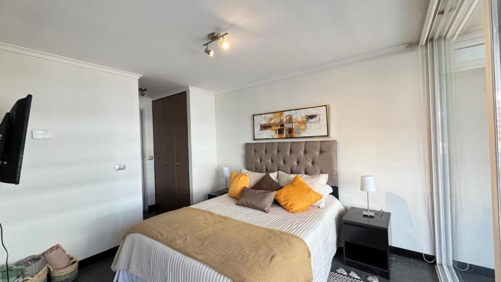 Un dormitorio con una cama con almohadas naranjas. en Mall Parq Arauco Tranquilo y Familiar Las Condes, en Santiago