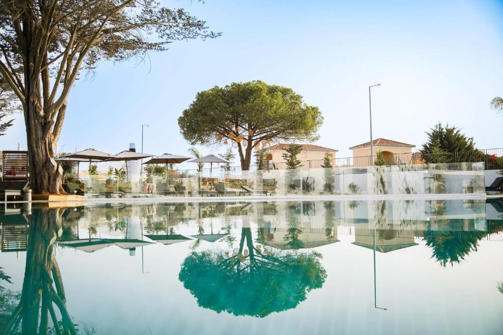 uma piscina de água com árvores e edifícios ao fundo em Castelo Suites Hotel em Albufeira