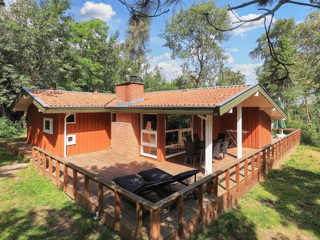 a house with a wooden deck in the grass at 5 star holiday home in Væggerløse in Bøtø By