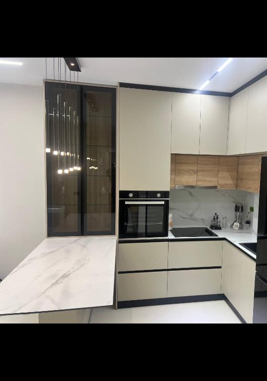 a kitchen with white cabinets and black appliances at Sweet HOME in Shëngjin