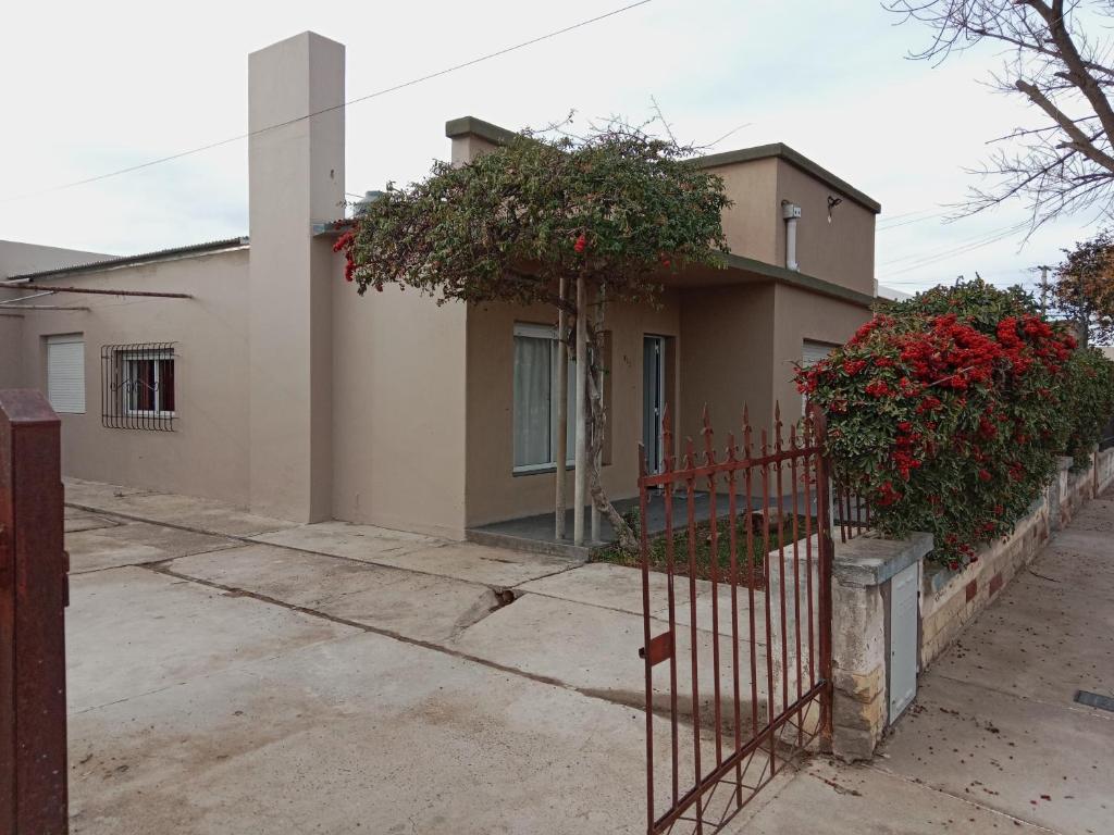 una casa con una valla y flores rojas en ella en Departamentos DOÑA ELBA, en Río Colorado