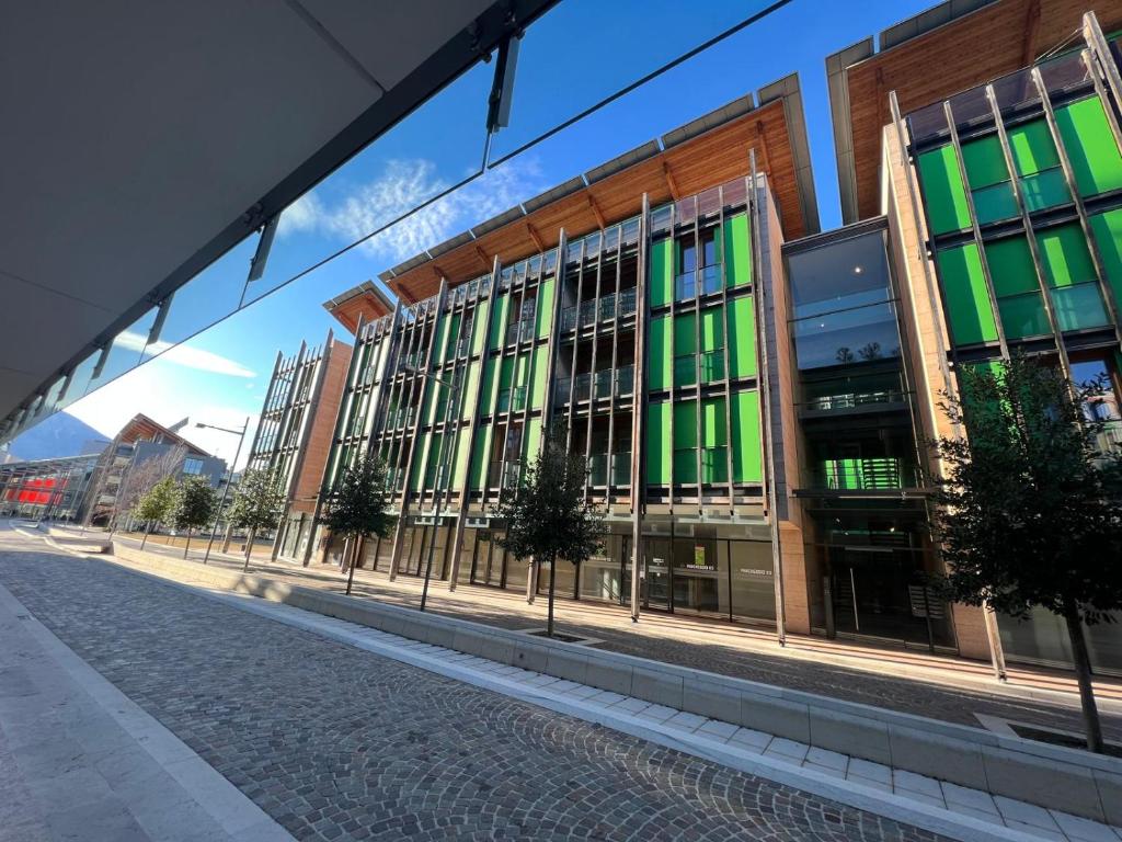 a large building with green windows on a street at Bilocale Yugogo Garden Park Le Albere in Trento