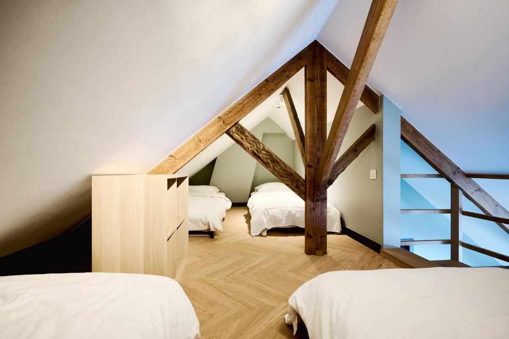 アウデナールデにあるSint-Jacobshoeve 2の3つのベッドと木製の梁がある屋根裏部屋の寝室