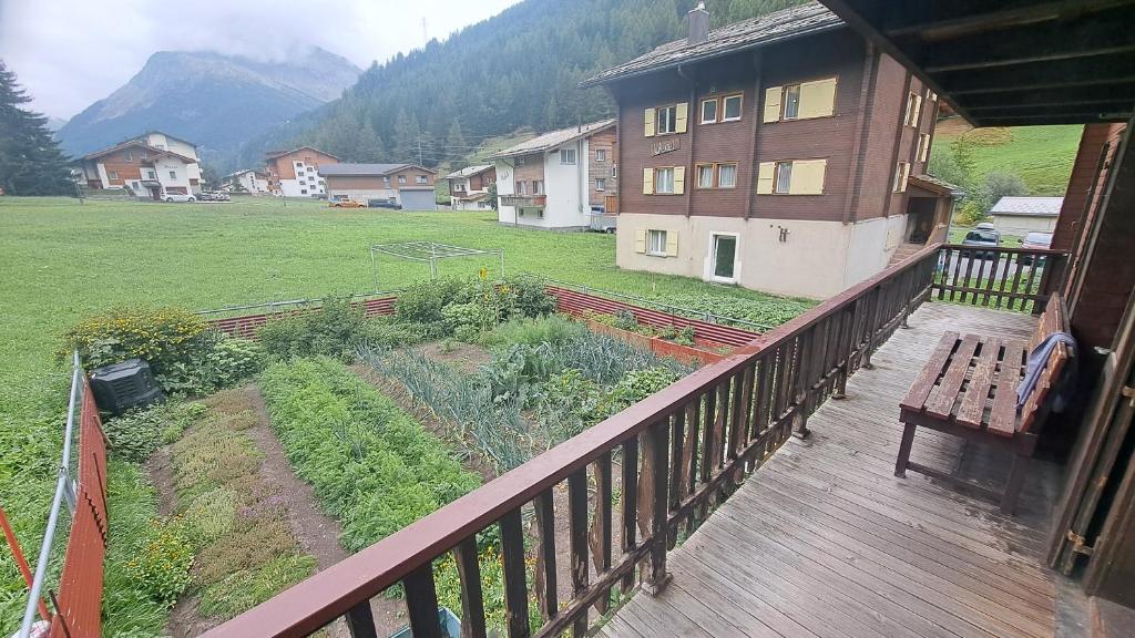 Una terraza con un banco y un jardín en una casa. en FREE Bus Winter Haus Ramona, en Saas-Grund