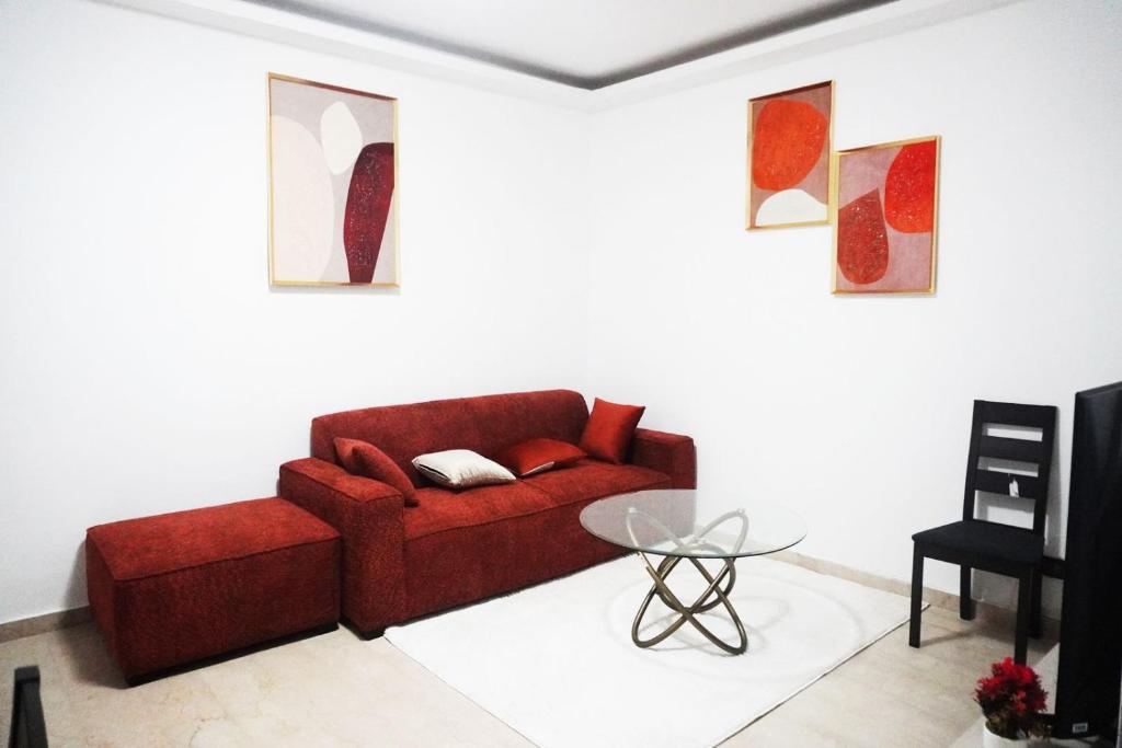 un soggiorno con un divano rosso e un tavolo di Les muguets de chaville a Abidjan