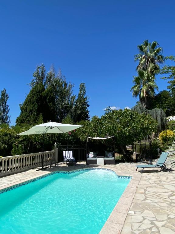 a swimming pool with two chairs and an umbrella at Chambre de charme climatisée, avec piscine in Grasse