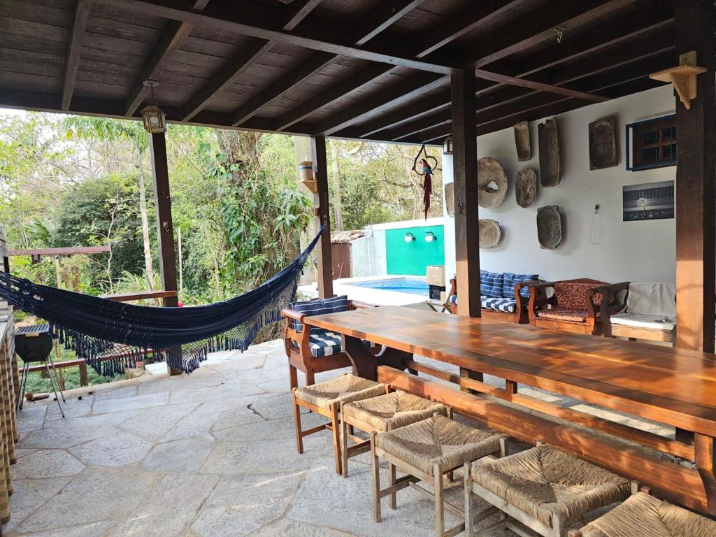 a patio with a hammock and a wooden table and chairs at Casa Galeria in Pirenópolis
