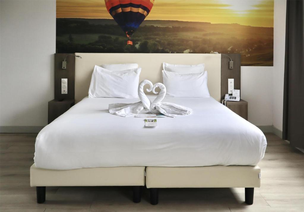 a bedroom with a bed with two swans on it at Best Western Hotel Ile de France in Château-Thierry