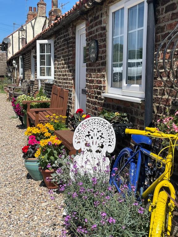 a house with a bench and flowers in front of it at Hayloft Sleep 2 NeXT to Fox Covert Pub in Kirk Leavington