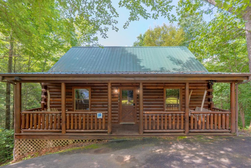 a log cabin with a porch and a green roof at Rosey Bear cabin in Pittman Center