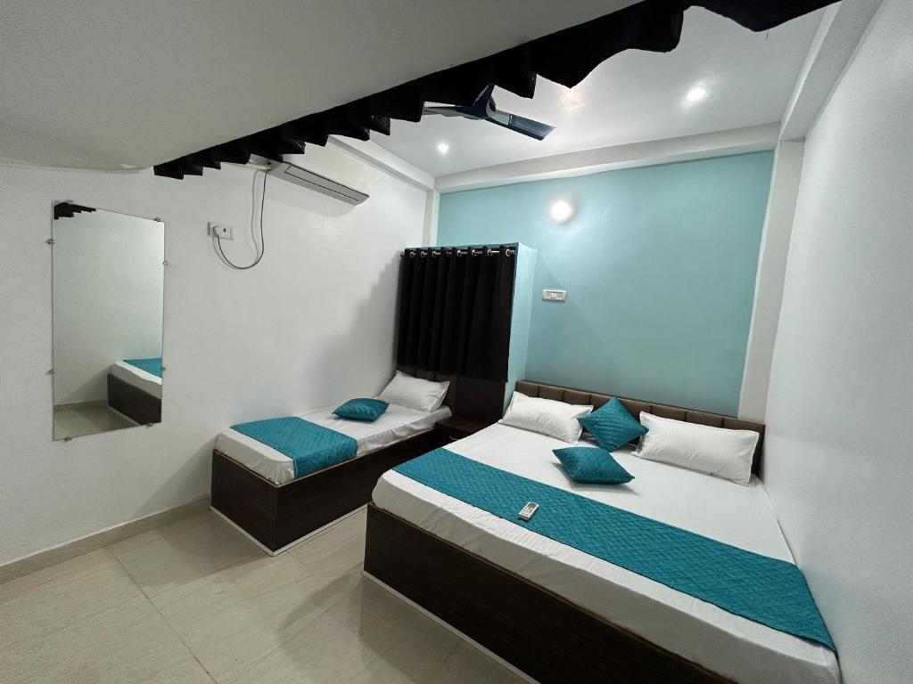 a bedroom with two beds and a mirror at Shree Gomukh residency comfortable home stay for family near to vishwanath temple 200 mtrs in Varanasi