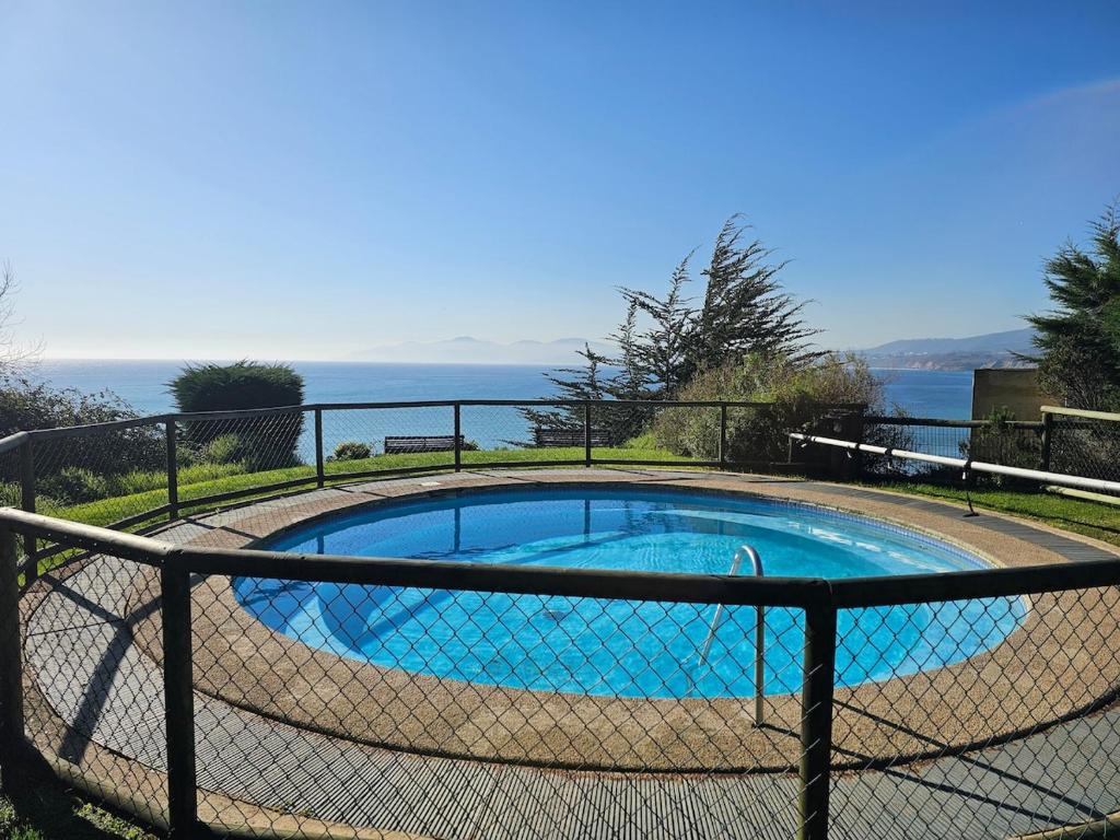 a small swimming pool with the ocean in the background at Departamento frente al mar, con piscinas y vista panorámica in Puchuncaví