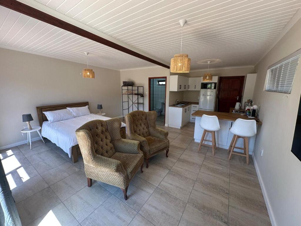 ウースターにあるWorcester accommodation Putt and Stayのベッドルーム1室(ベッド1台、椅子2脚付)、キッチンが備わります。