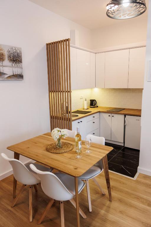 a kitchen with a wooden table and white cabinets at Apartman Bonus in Palić