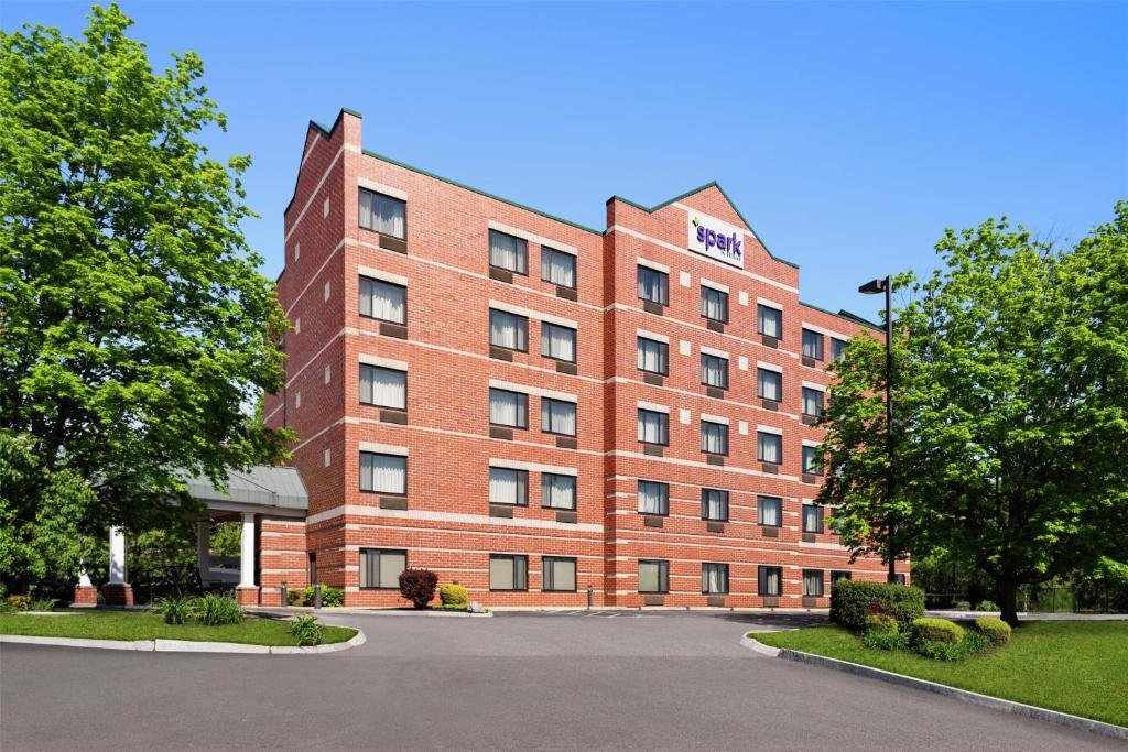 un edificio de ladrillo rojo con árboles delante de él en Spark by Hilton Woburn Boston, en Woburn