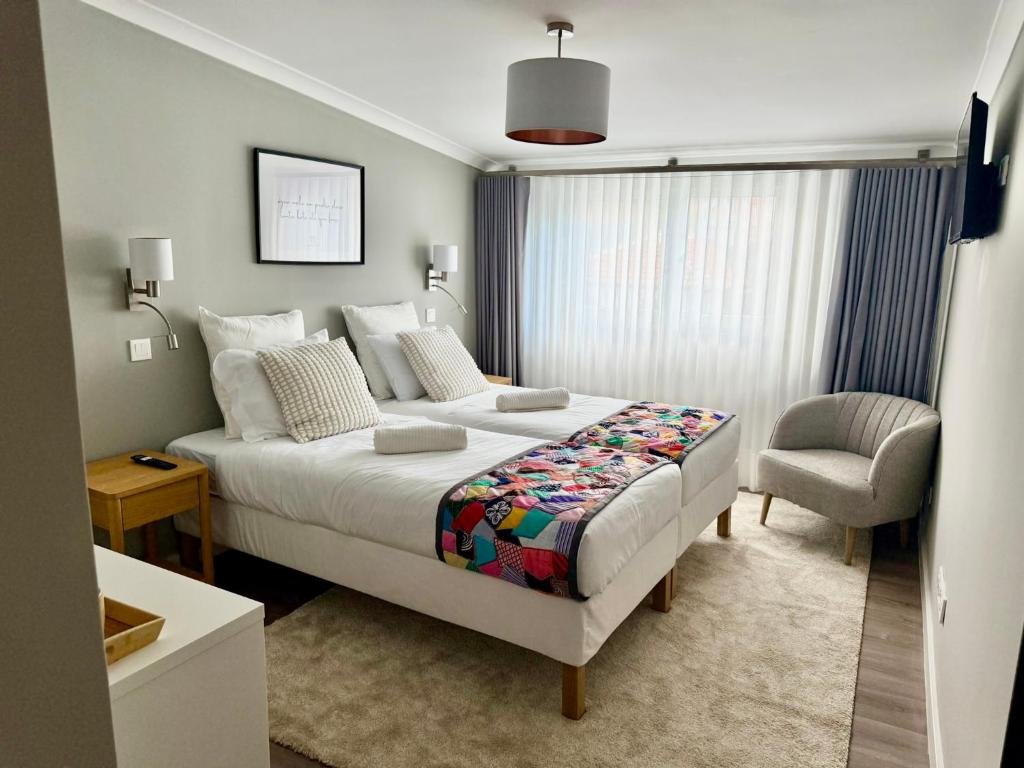 a bedroom with a large bed and a chair at Vera Cruz Guesthouse in Angra do Heroísmo