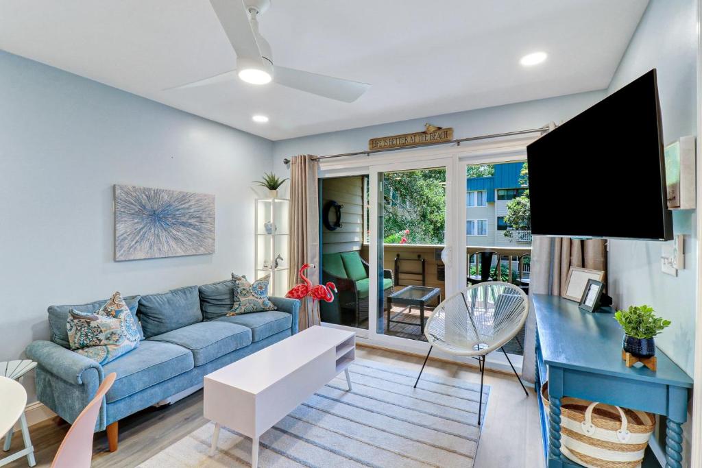 un salon avec un canapé bleu et une télévision à écran plat dans l'établissement Stunning 2 Bedroom Villa Steps to the Beach, à Île de Hilton-Head