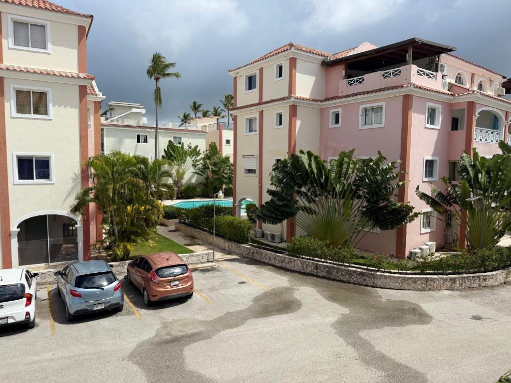 um grande edifício rosa com carros estacionados num parque de estacionamento em Riche luxury em Punta Cana