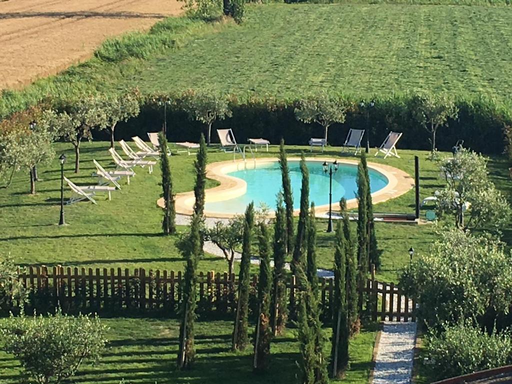 een zwembad in een veld met stoelen en bomen bij B&B Antica Dimora in San Giuliano Terme