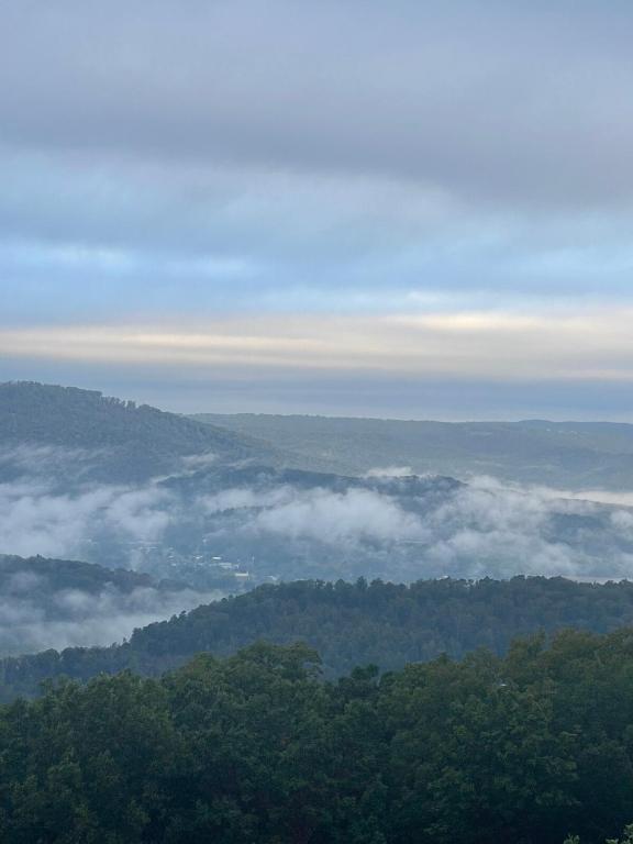 a view of a valley of clouds and trees at Lookout Mtn cabin with a view in Rising Fawn