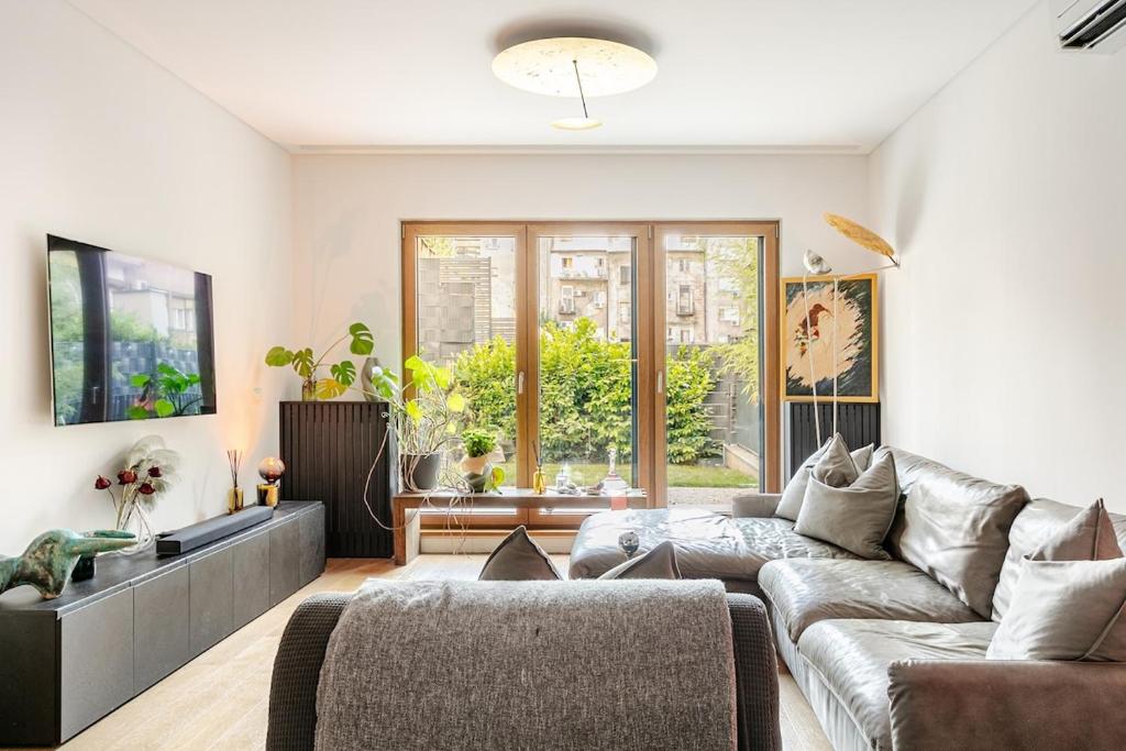 a living room with a couch and a large window at Garden Oasis in City Center in Belgrade
