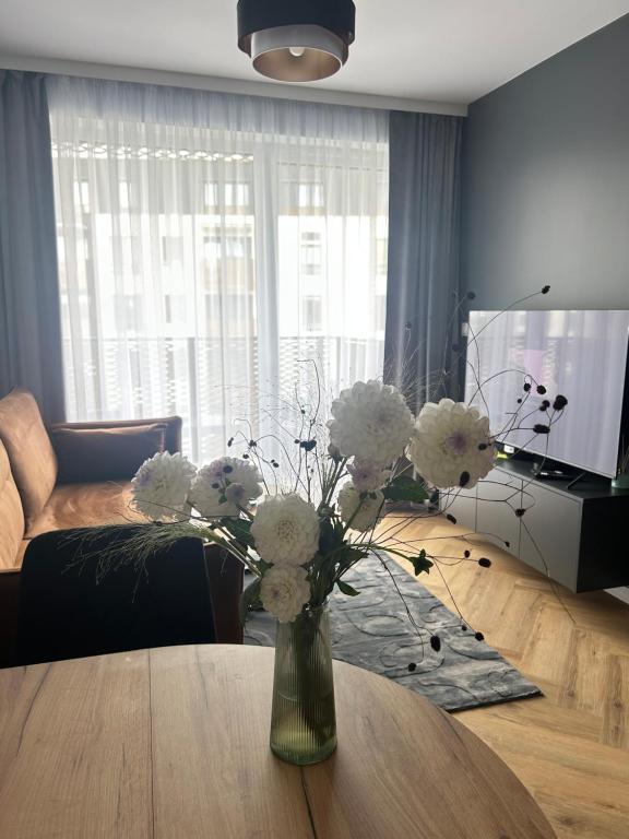 a vase with white flowers on a table in a living room at Apartament Grafitowy in Nysa