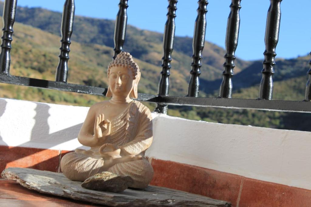 a statue of a buddha sitting on a ledge at The Retreat, Alcazar in Órgiva