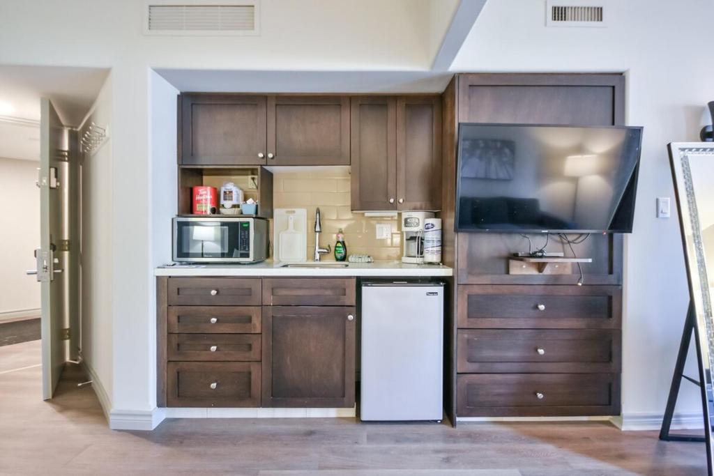 une cuisine avec des armoires en bois et un réfrigérateur blanc dans l'établissement The King Studio Sauna Haven, à Shanty Bay