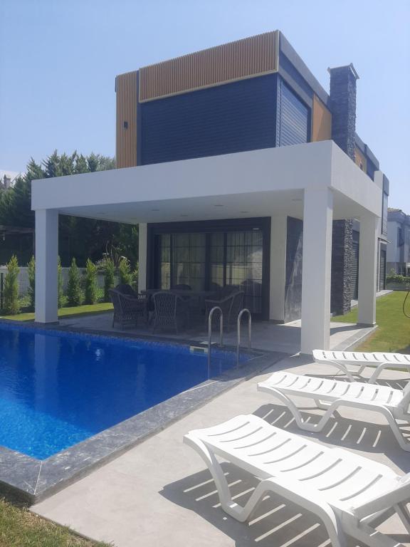 una casa con piscina e sedie a sdraio bianche di Villa Vogue 