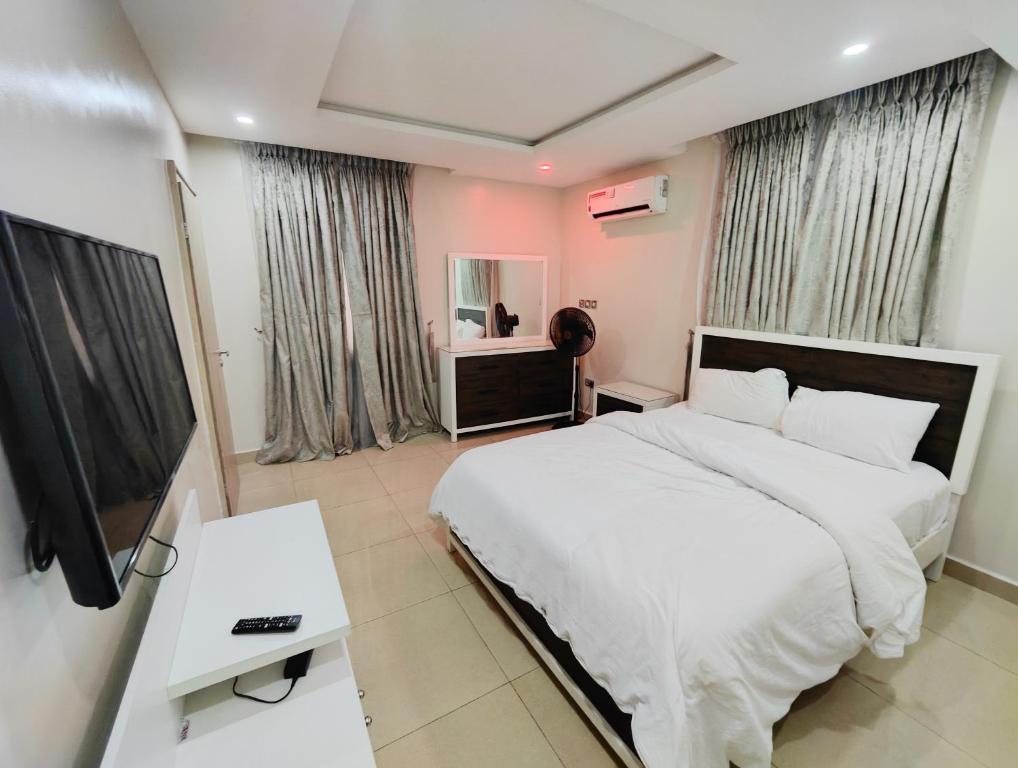 a bedroom with a bed and a flat screen tv at Royal 3 Bedroom Apartment with 24hrs Power Supply, Wifi, Security and Fully Equipped Kitchen in Lekki