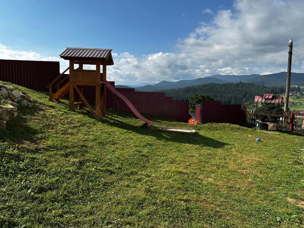 a playground with a slide in the grass at Затишний будинок in Vorokhta