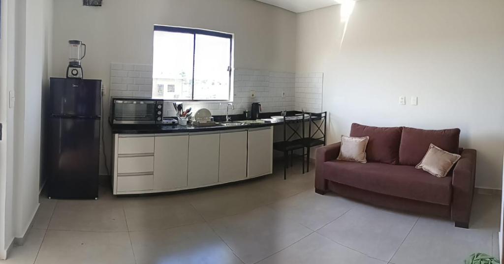 Una sala de estar con un sofá y una cocina. en Apartamento costa Penna, en Santa Rita