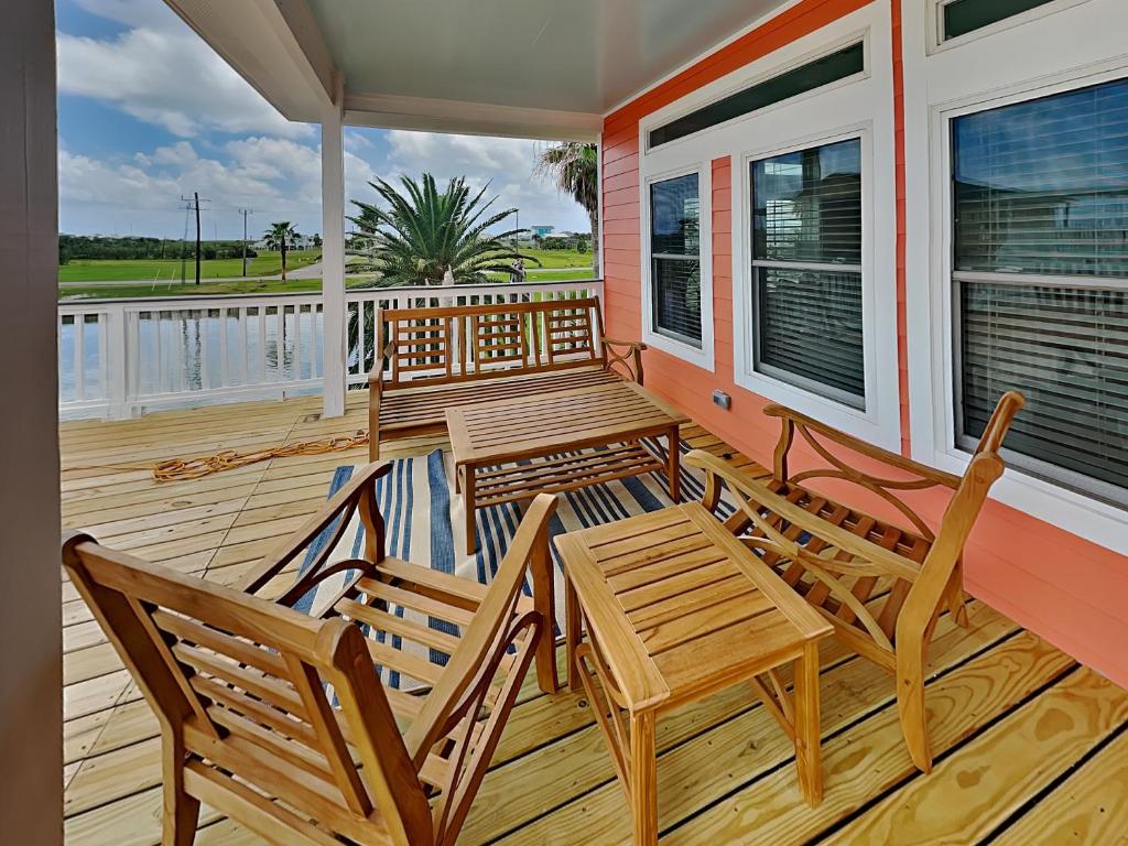 a porch with two wooden chairs and a table at West Bay Getaway in Galveston
