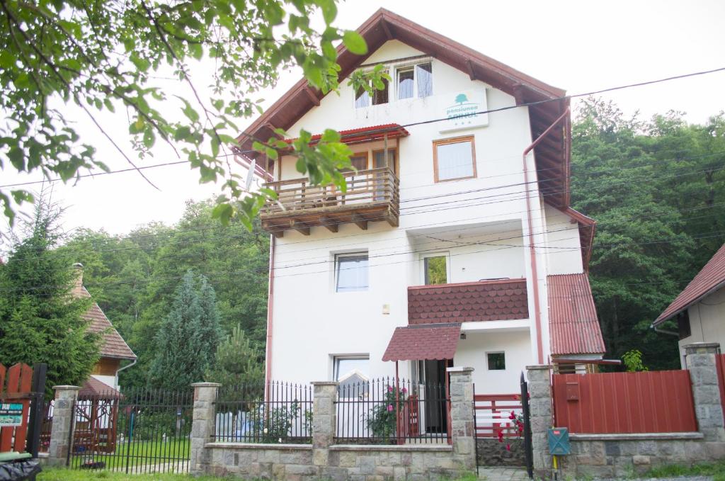 ein weißes Haus mit einem Balkon und einem Zaun in der Unterkunft Pensiunea Arinul in Sovata