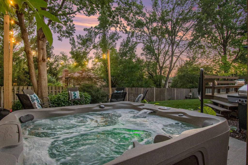 a hot tub in a backyard with a table and a bench at Central Family Oasis with Hot Tub & Fenced Yard in Omaha