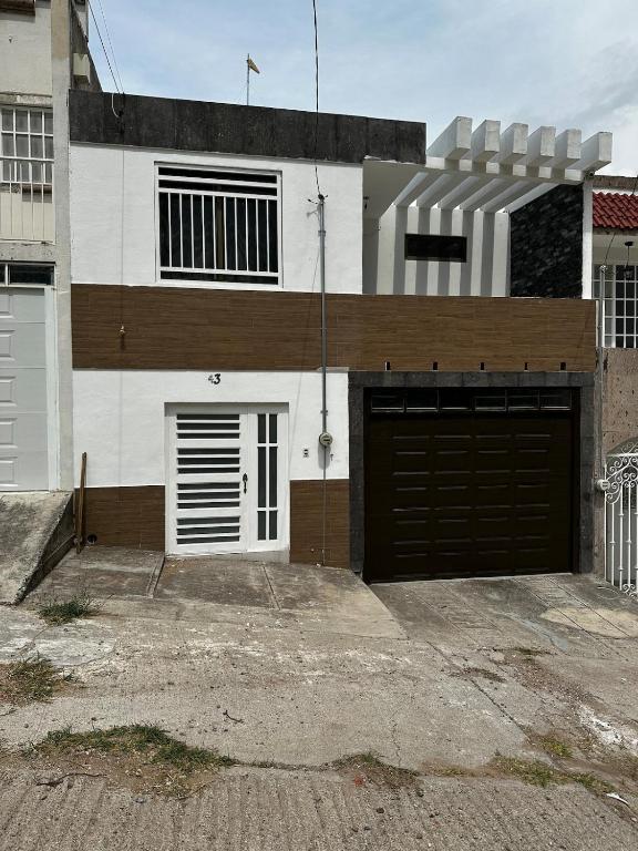 a white and brown house with two garage doors at Casa muy cómoda de 2 pisos en zona muy tranquila in Media Fanega