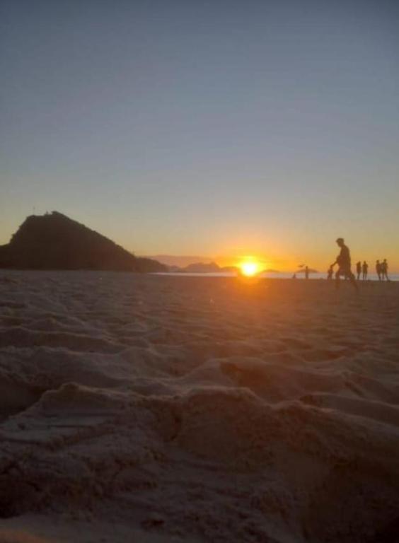 a group of people walking on the beach at sunset at VILA LEME Casa 11A in Rio de Janeiro