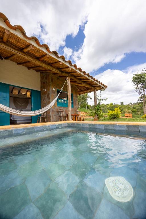 an outdoor swimming pool with a hammock in front of a house at Buratá Haus Hotel Boutique in Barichara