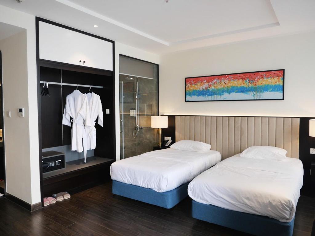 Hạ Long Sapphire Premium في ها لونغ: غرفة فندقية بسريرين ومرآة