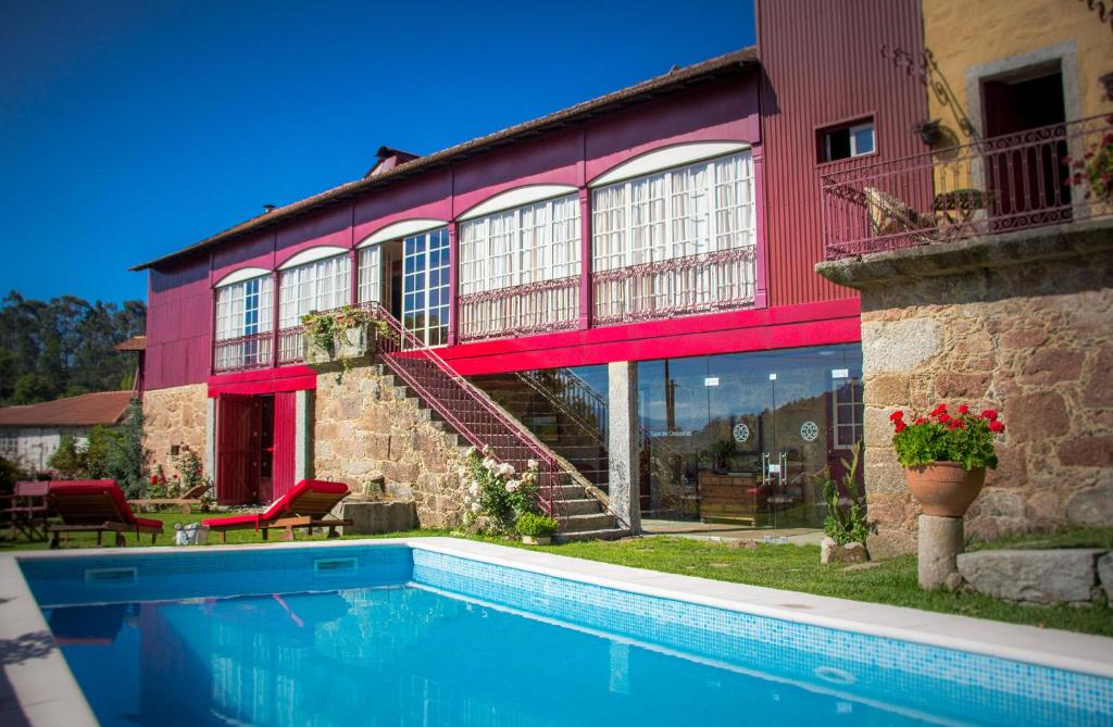 uma casa com piscina em frente a um edifício em Casa de Chouselas em Vilela